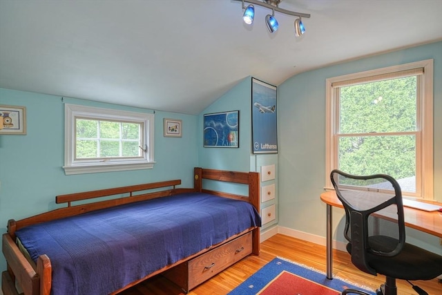 bedroom featuring wood finished floors, lofted ceiling, and baseboards