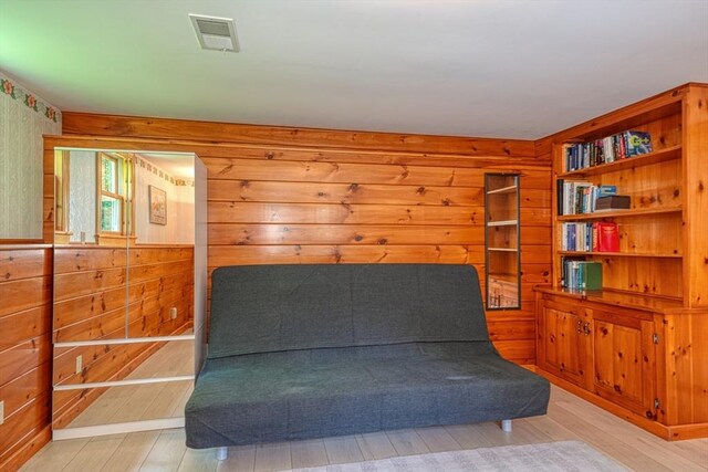 living area with wooden walls and light wood finished floors