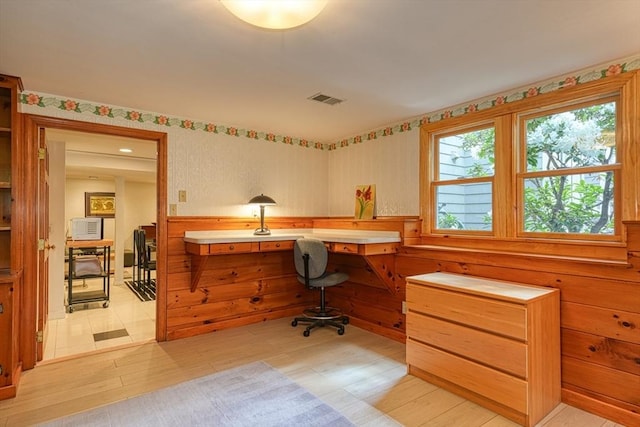 home office featuring plenty of natural light, built in desk, and a wainscoted wall