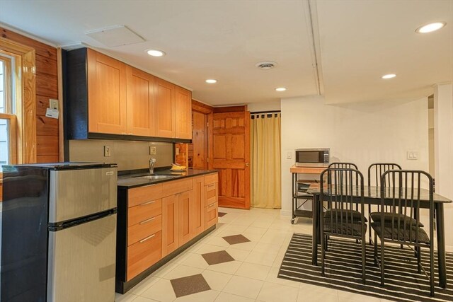 kitchen featuring appliances with stainless steel finishes, a sink, dark countertops, recessed lighting, and light tile patterned floors