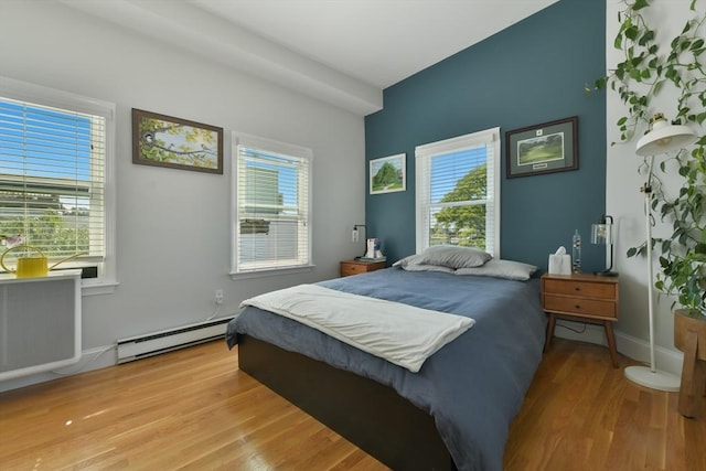 bedroom featuring light wood-type flooring, a baseboard radiator, and baseboards