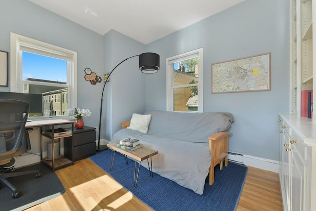 living room featuring a baseboard radiator, light wood-style flooring, and baseboards