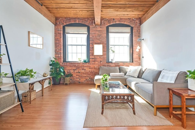 living area with wood finished floors, beam ceiling, wooden ceiling, and brick wall