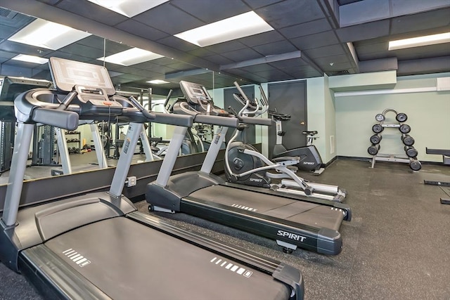 gym featuring baseboards and a drop ceiling