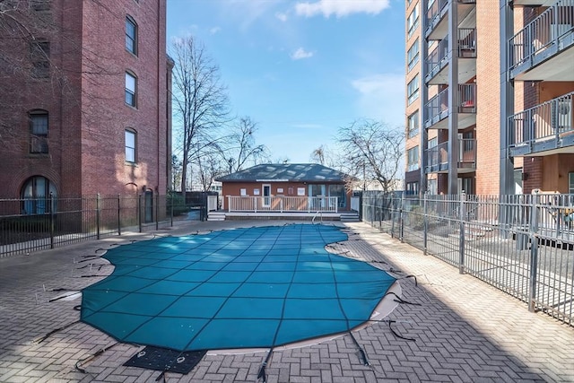 community pool with a patio area and fence