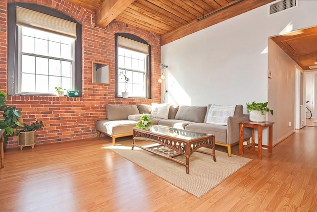 living room with wood finished floors, visible vents, brick wall, wood ceiling, and beamed ceiling