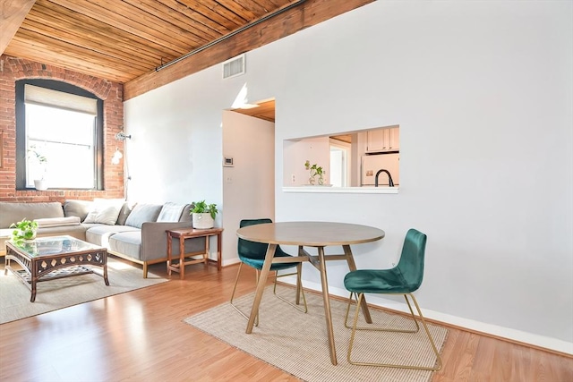 interior space with wooden ceiling, wood finished floors, visible vents, and brick wall