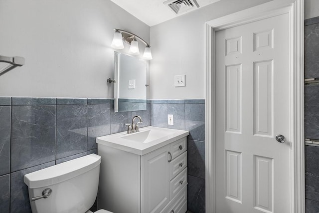 bathroom with vanity, tile walls, and toilet