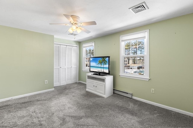 unfurnished bedroom featuring ceiling fan, a closet, carpet, and a baseboard heating unit