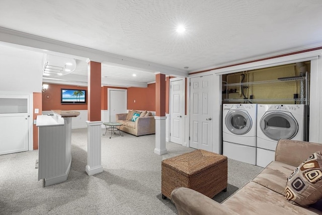 laundry room featuring decorative columns, light colored carpet, washer and dryer, and a textured ceiling