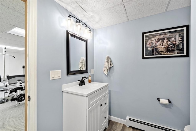 51 Carrie Ann Ln, Fitchburg, MA 01420 - bathroom featuring a paneled ceiling, a baseboard heating unit, vanity, and wood finished floors