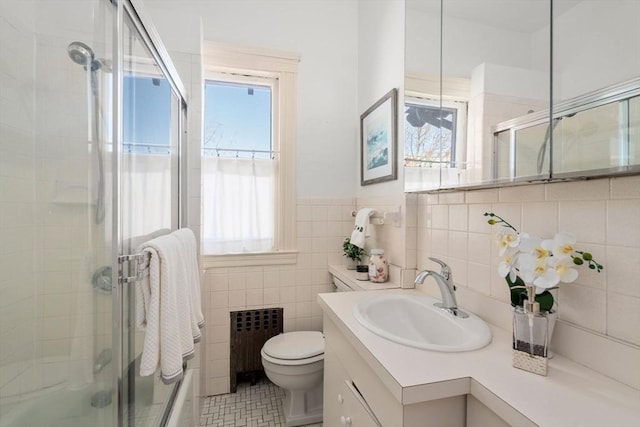 bathroom with tile walls, vanity, an enclosed shower, toilet, and radiator