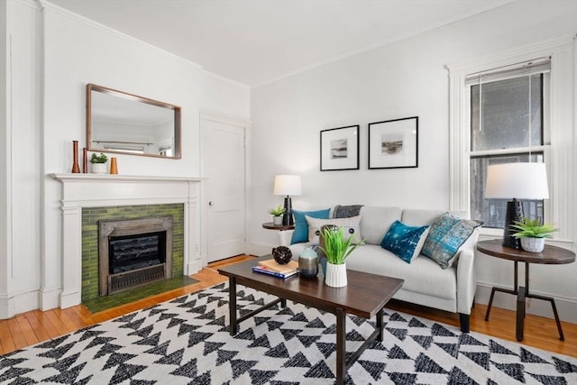 living room featuring ornamental molding, a tiled fireplace, and hardwood / wood-style floors