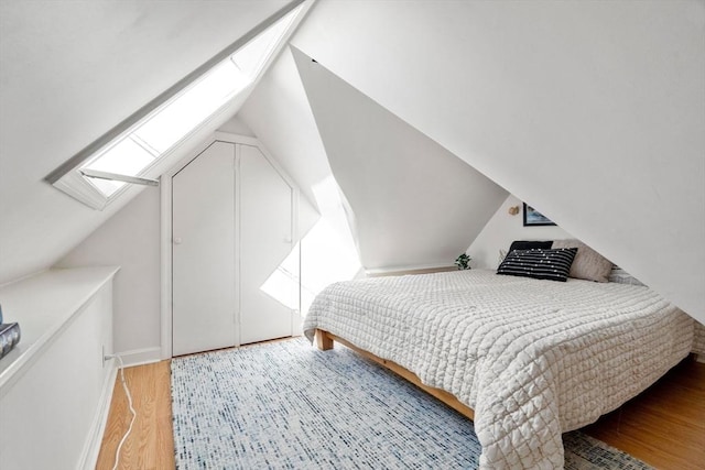 bedroom with vaulted ceiling with skylight and wood-type flooring