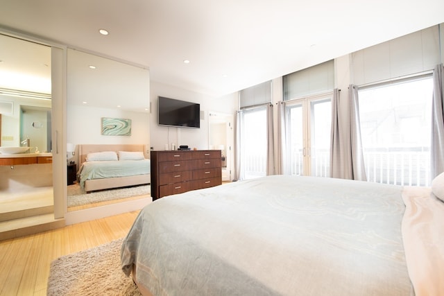 bedroom featuring connected bathroom and light hardwood / wood-style floors