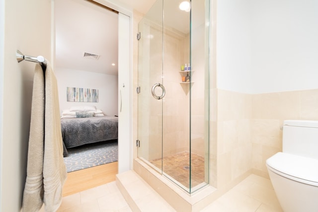 bathroom with toilet, an enclosed shower, and tile patterned flooring