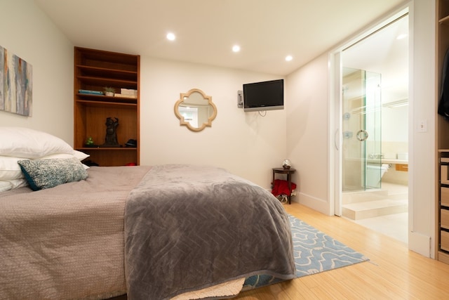 bedroom featuring connected bathroom and light hardwood / wood-style floors