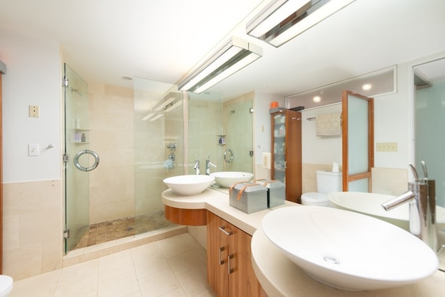 bathroom featuring vanity, toilet, tile patterned flooring, and a shower with door