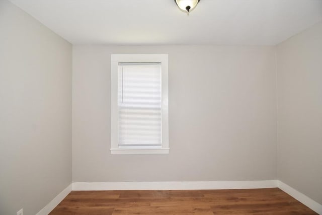 spare room featuring baseboards and wood finished floors
