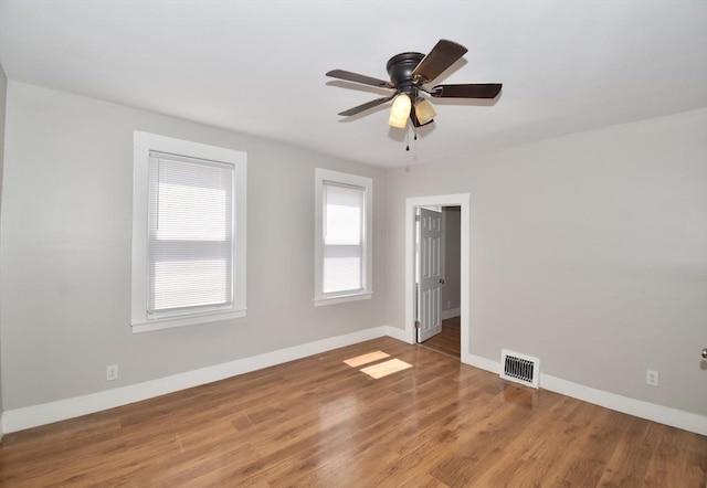 unfurnished room with baseboards, wood finished floors, and a ceiling fan