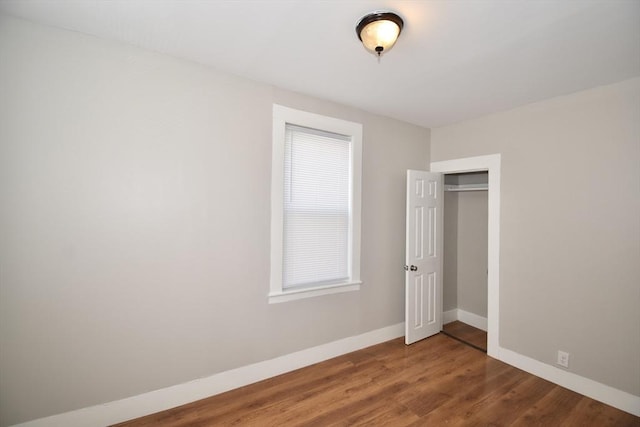 unfurnished bedroom with baseboards, wood finished floors, and a closet