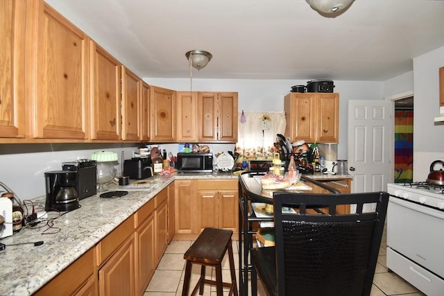kitchen with white gas range, light tile patterned floors, and light stone countertops