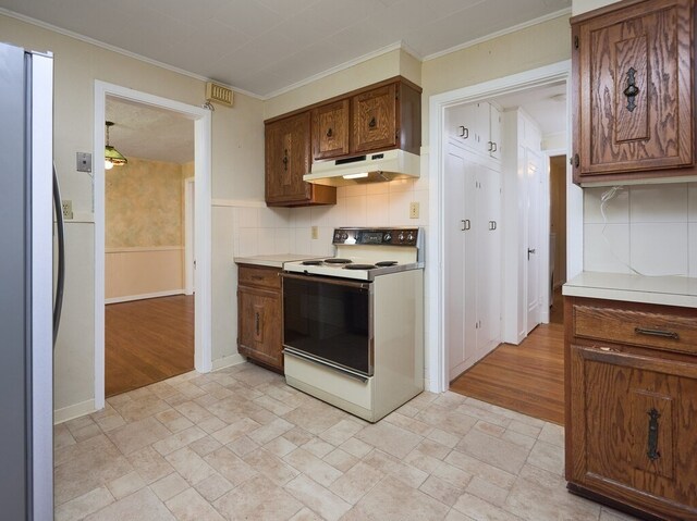 kitchen featuring light wood-type flooring, tasteful backsplash, white electric range oven, and stainless steel refrigerator