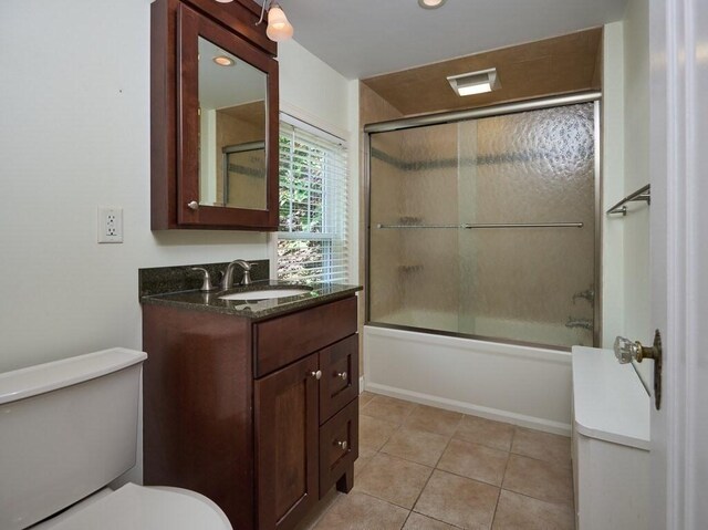 full bathroom with toilet, tile patterned floors, vanity, and bath / shower combo with glass door