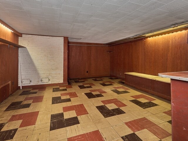 basement featuring light tile patterned flooring and wooden walls