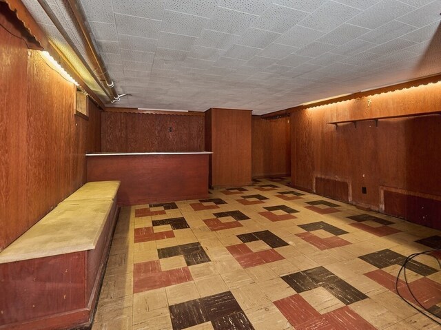 basement featuring light tile patterned flooring and wooden walls