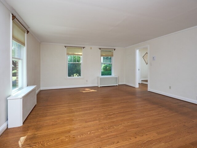 unfurnished living room with radiator, crown molding, and wood-type flooring