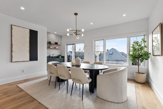 dining area with a chandelier, sink, and light hardwood / wood-style flooring