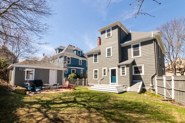 back of property featuring an outbuilding, a patio area, fence, and a yard