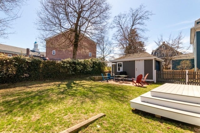view of yard featuring a deck, fence, an outbuilding, and a patio