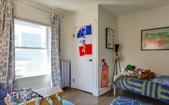 bedroom featuring radiator heating unit and wood finished floors