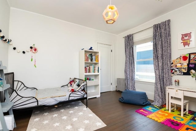 bedroom with crown molding, wood finished floors, and radiator heating unit
