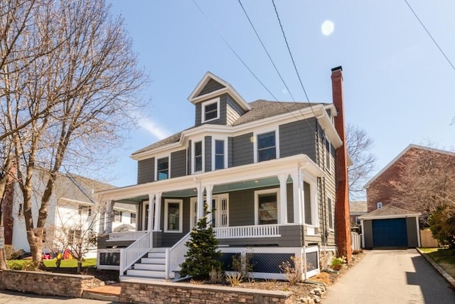 traditional style home with a garage, an outbuilding, a chimney, covered porch, and driveway