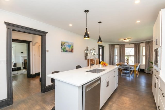 kitchen with stainless steel dishwasher, a sink, light countertops, white cabinets, and dark wood-style floors