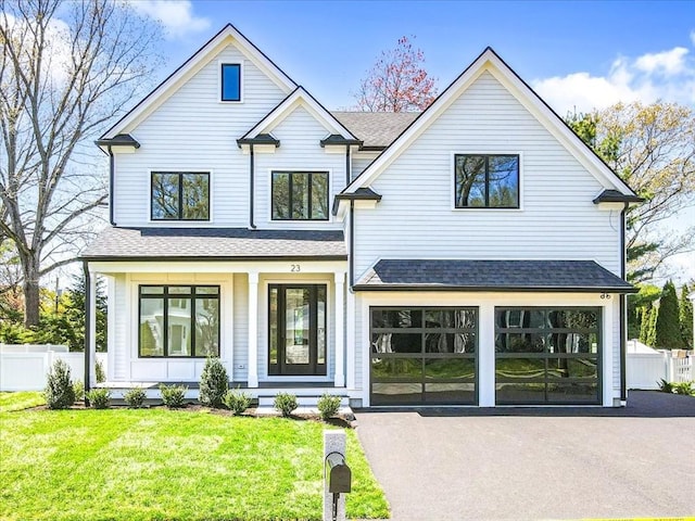 modern inspired farmhouse with fence, driveway, a front yard, and roof with shingles