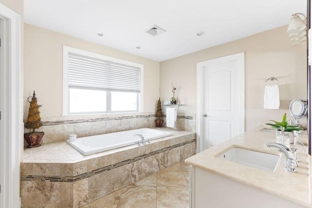 bathroom with double vanity, visible vents, a garden tub, tile patterned flooring, and a sink