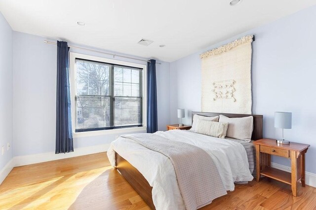 bedroom featuring wood finished floors, visible vents, and baseboards