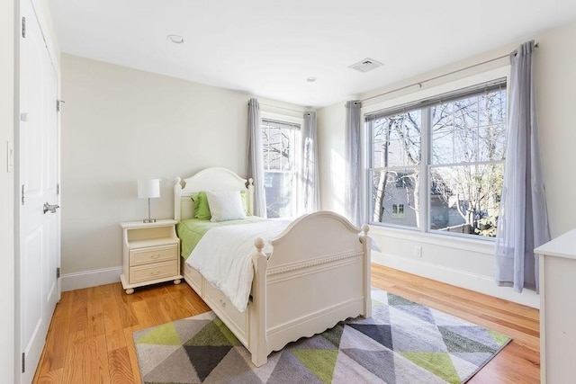 bedroom with light wood-style floors, visible vents, and baseboards