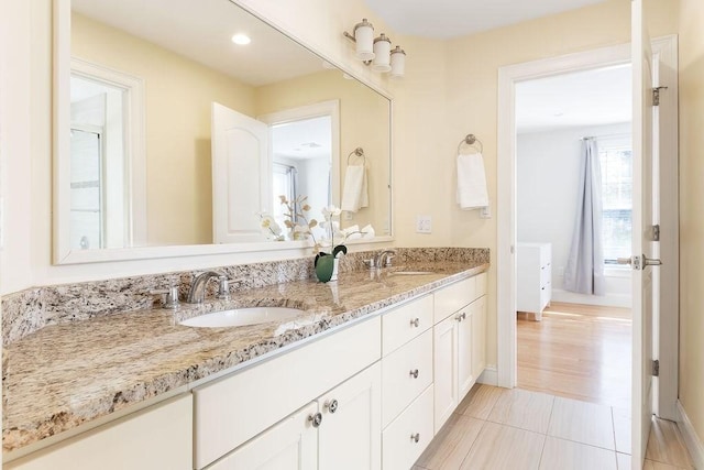 full bath with double vanity, a sink, and baseboards