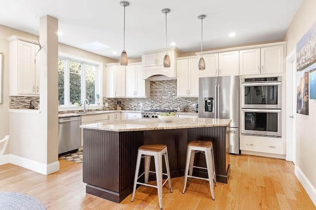 kitchen with a breakfast bar, white cabinetry, appliances with stainless steel finishes, backsplash, and a center island