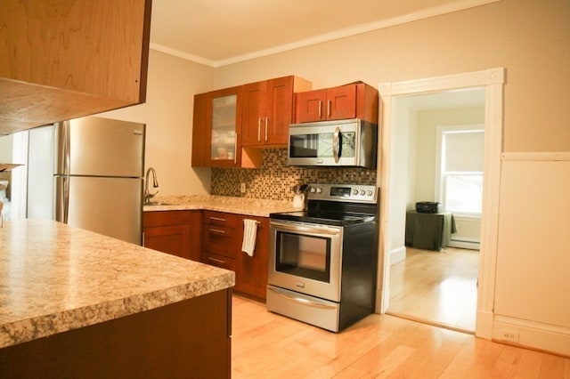 kitchen with tasteful backsplash, crown molding, stainless steel appliances, light wood-type flooring, and sink