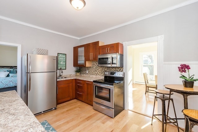 kitchen featuring sink, ornamental molding, appliances with stainless steel finishes, backsplash, and light hardwood / wood-style floors