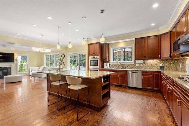 kitchen featuring appliances with stainless steel finishes, open floor plan, light stone counters, backsplash, and a high end fireplace