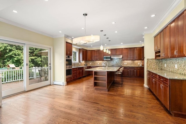 kitchen featuring a center island with sink, wood finished floors, light stone countertops, under cabinet range hood, and open shelves