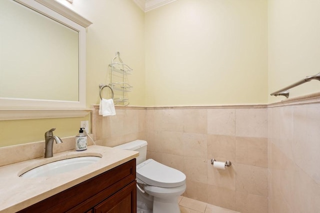 half bathroom featuring wainscoting, vanity, toilet, and tile walls