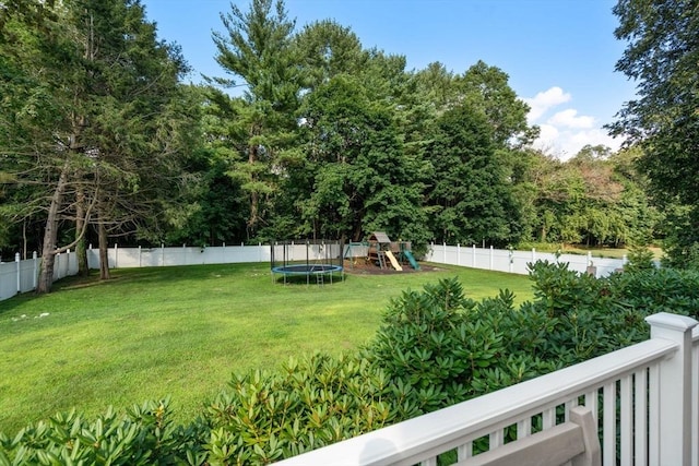 view of yard featuring a trampoline, a playground, and a fenced backyard